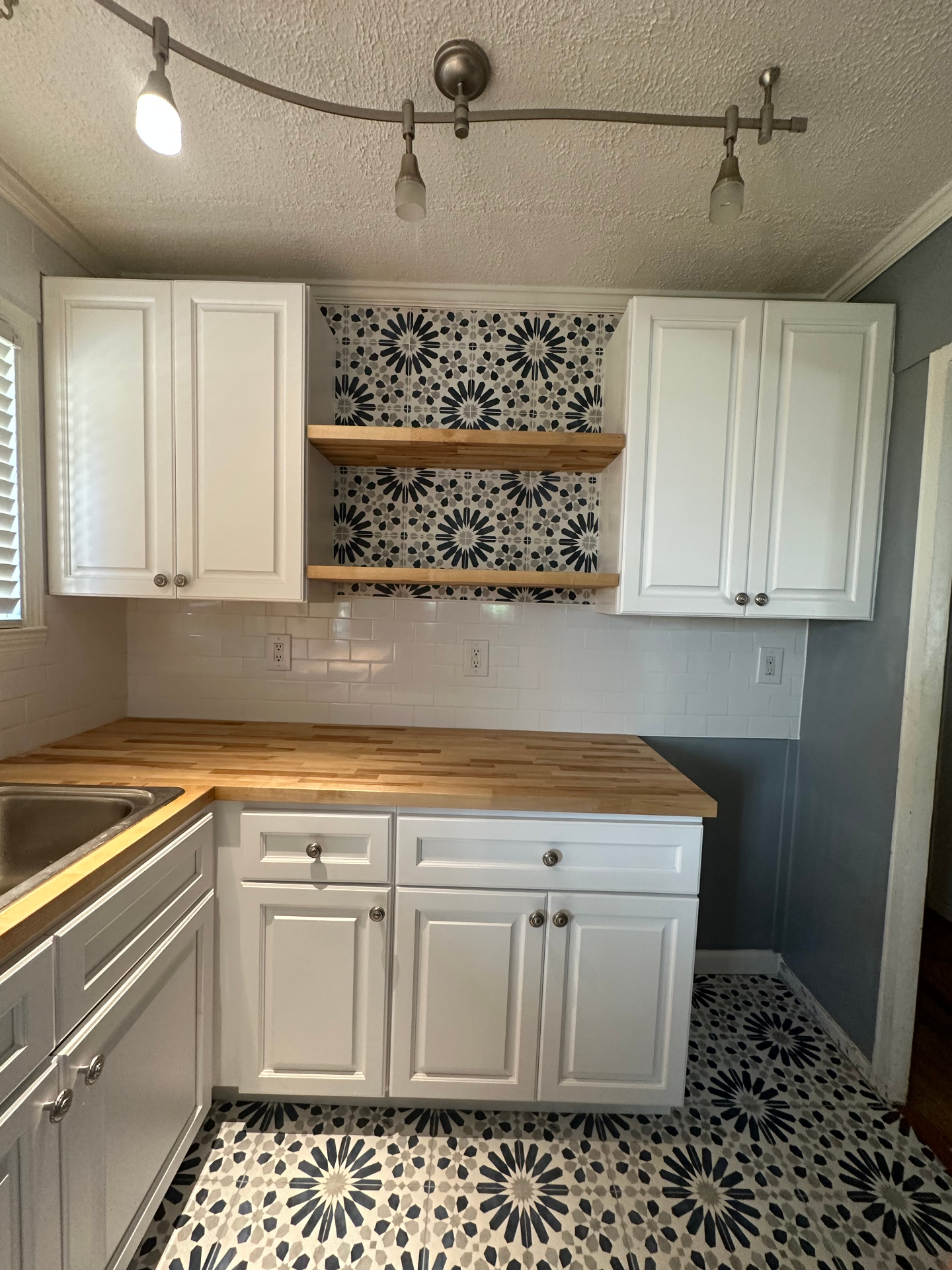 Butcher block countertops with decorative tile accent and open shelving